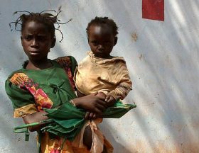 Girl carrying baby in front of the Zanga health centre22 by hdptcar CC BY 2.0 2 640x600 1