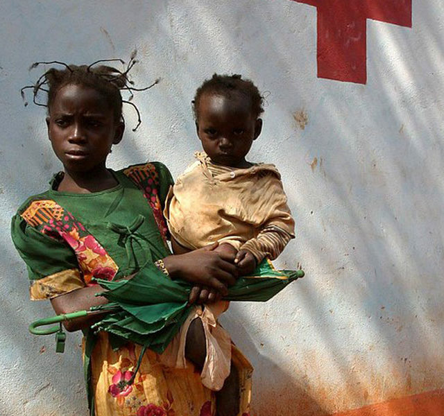 Girl carrying baby in front of the Zanga health centre22 by hdptcar CC BY 2.0 2 640x600 1